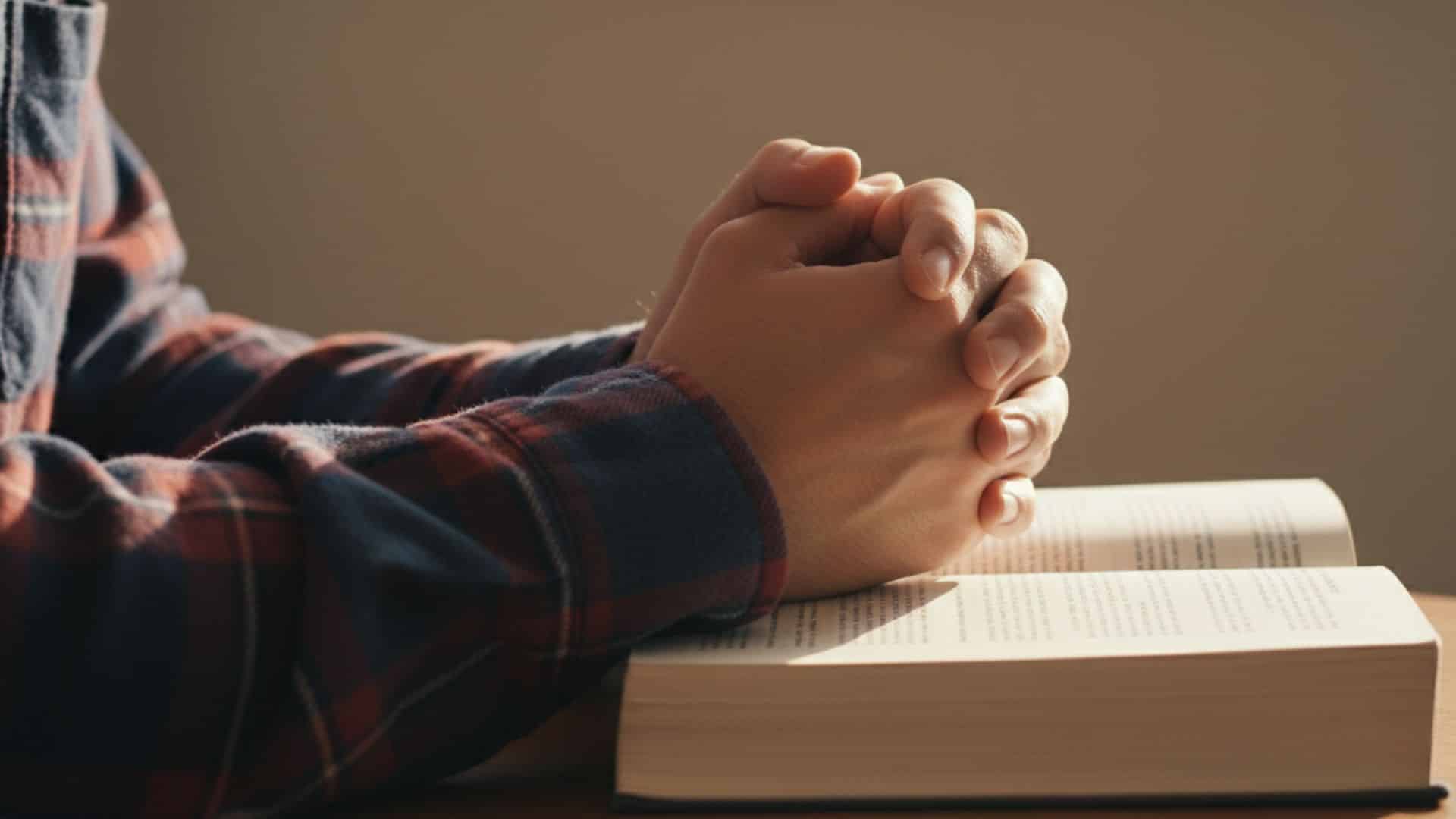 hands-clasped-in-prayer-over-open-bible